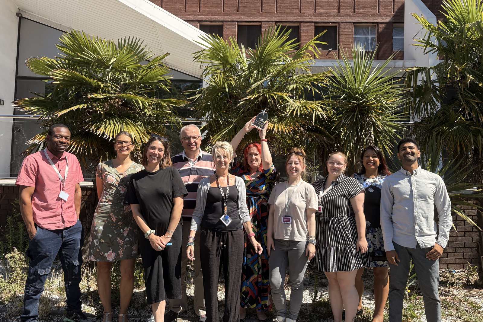 Our claims team outside the Poole office, with the trophy held up high