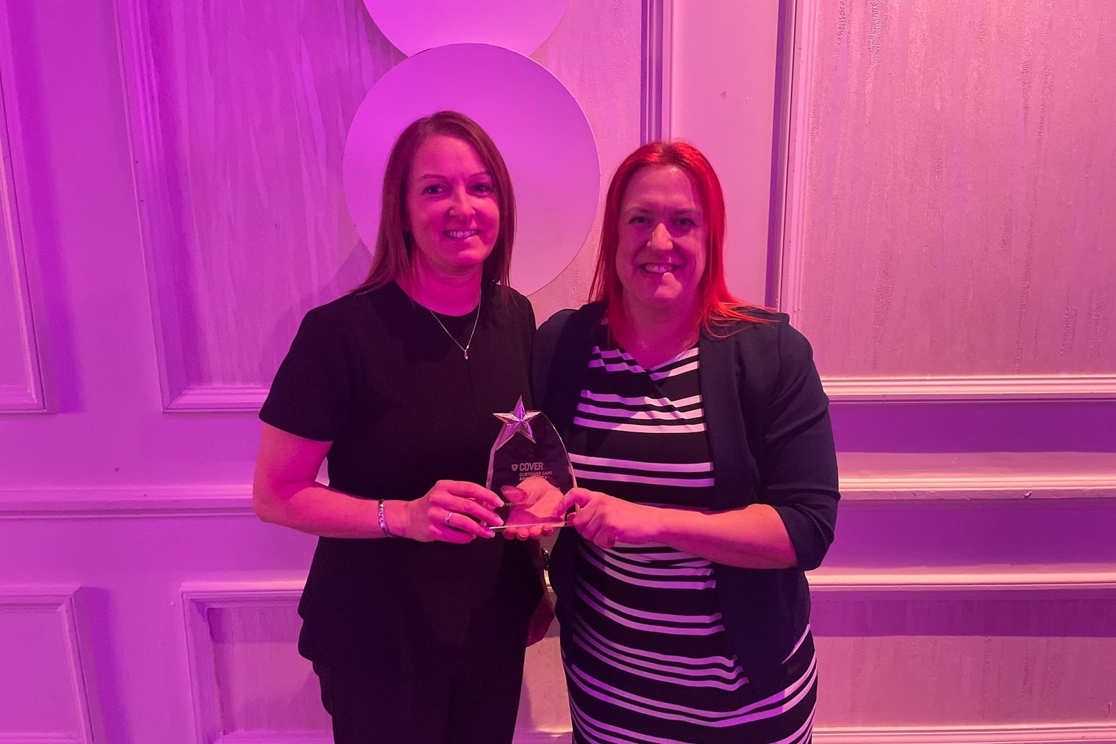 Two members of our team holding a COVER Customer Care Award at the awards evening