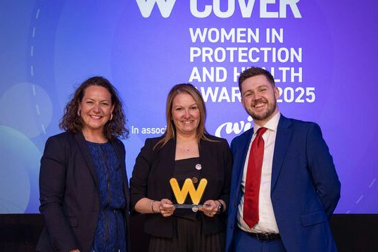 Our Woman of the Year, Customer Support, on stage holding her award, with two presenters