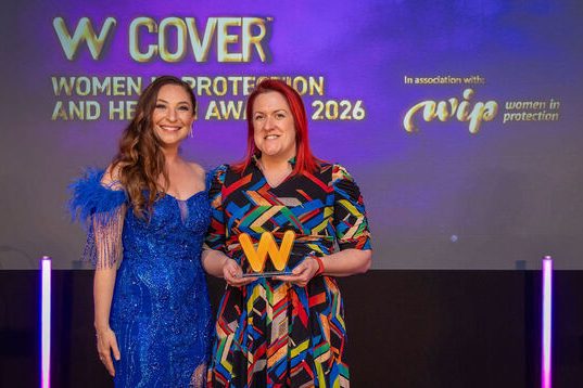Our Woman of the Year, Claims, on stage holding her award, with the event host