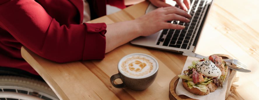 Person Working From Home On Laptop Having A Snack And Coffee 