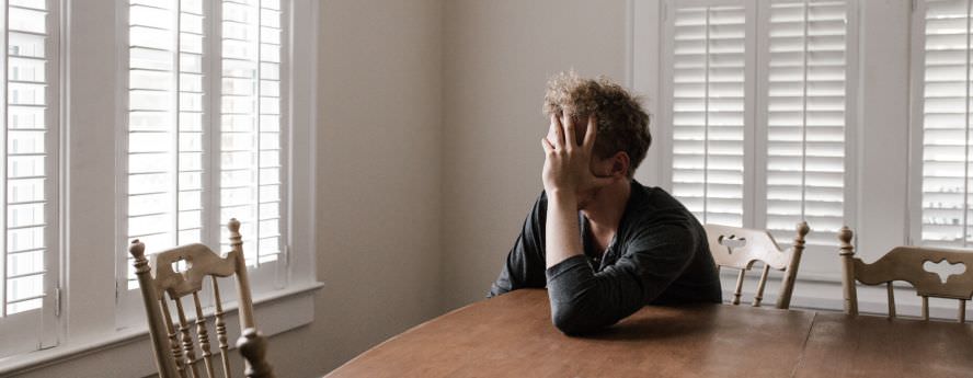 Men Sitting At The Table Holding His Head Feeling Lonely And Isolated 