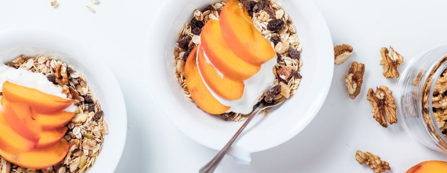 Healthy Breakfast Of Cereals With Fresh Fruit Pitches Nuts And Cream Bowl On White Table